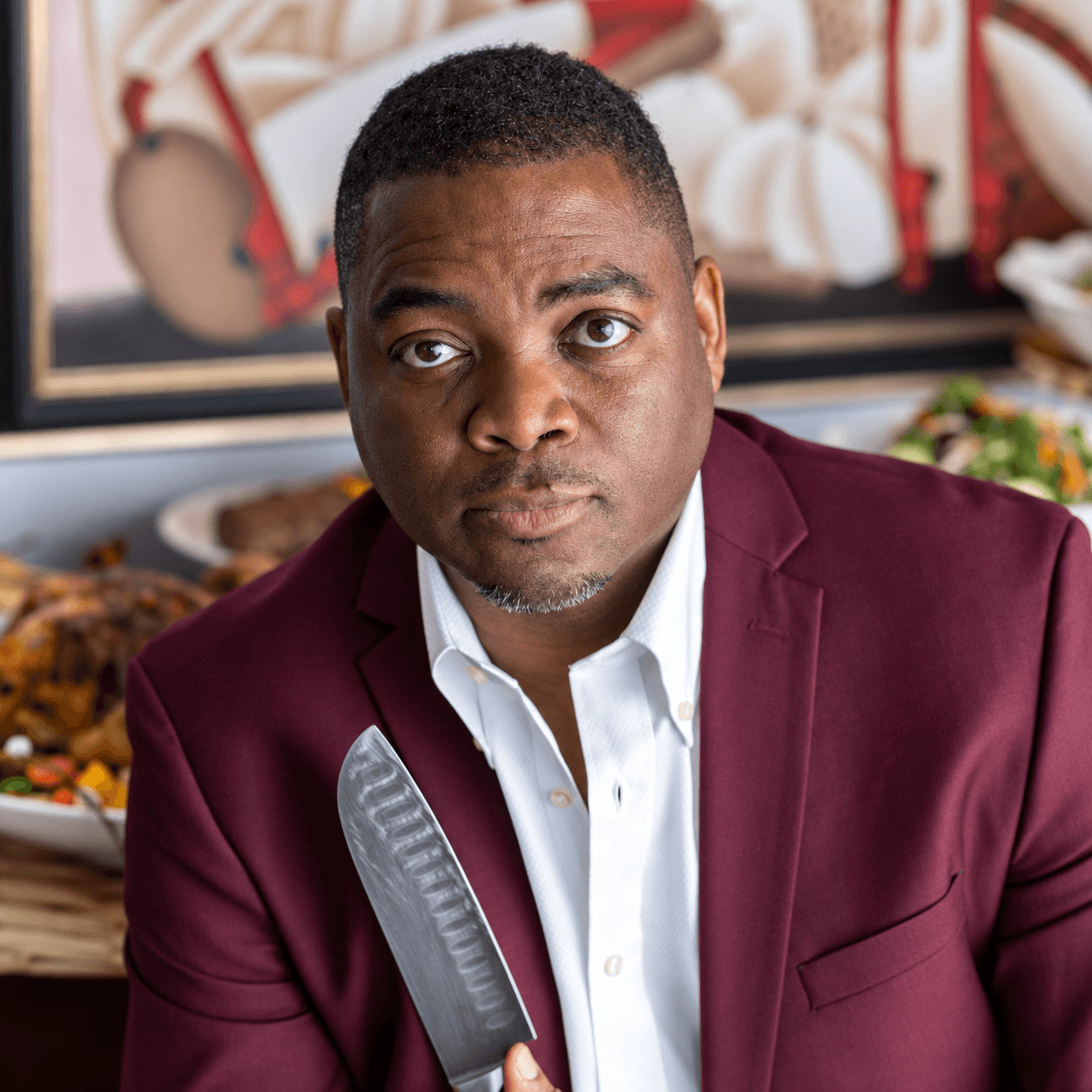 Chef Sean in a burgundy jacket holding a chef's knife